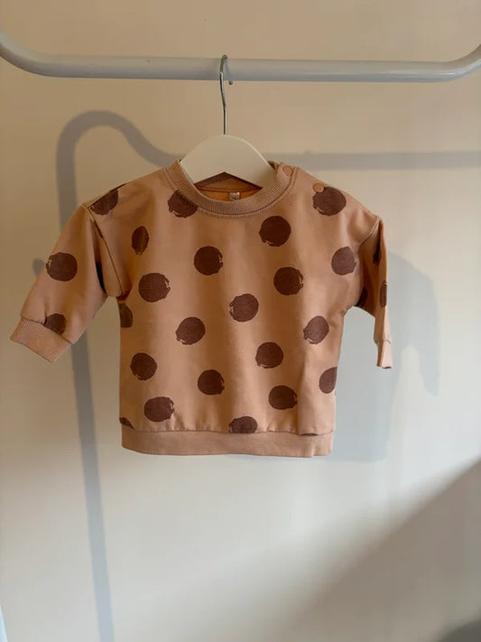 Pasteloranje sweater met bruine bollen